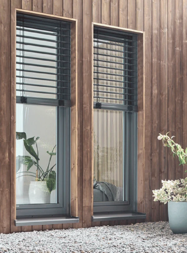 Zwei schmale hohe Fenster in einer Holzfassade